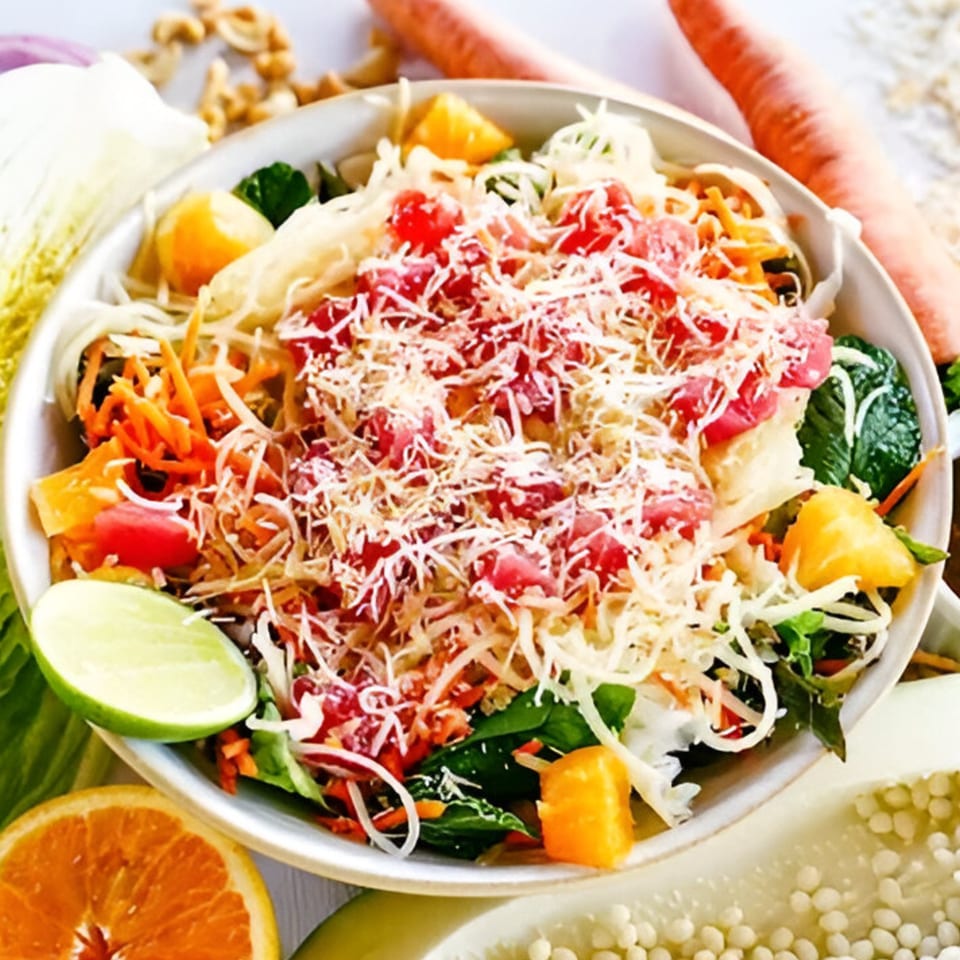 A vibrant Stoke Salad with shredded vegetables, red fruit, and grated cheese, garnished with lime.