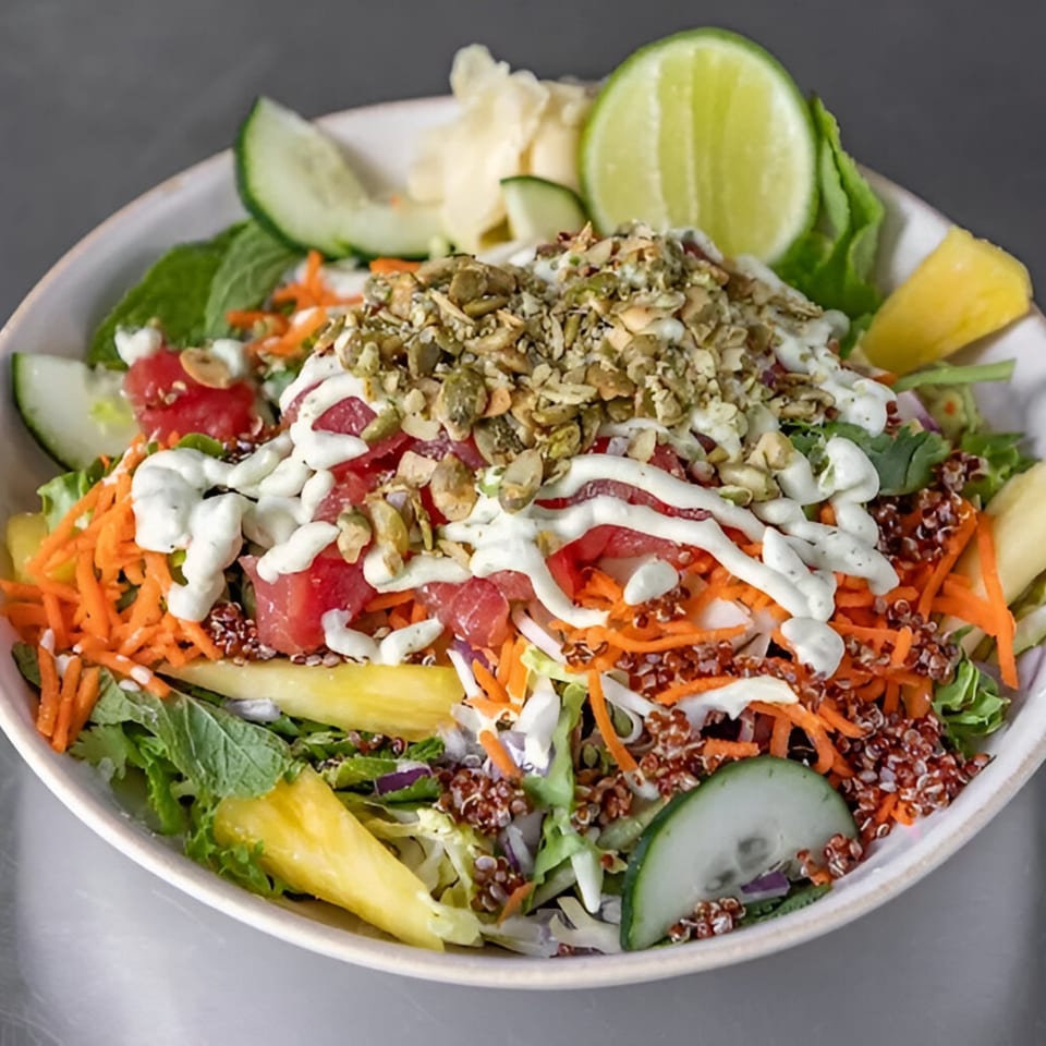 A vibrant Stoke Salad with quinoa, carrots, pineapple, cucumber, and a creamy dressing, topped with seeds.