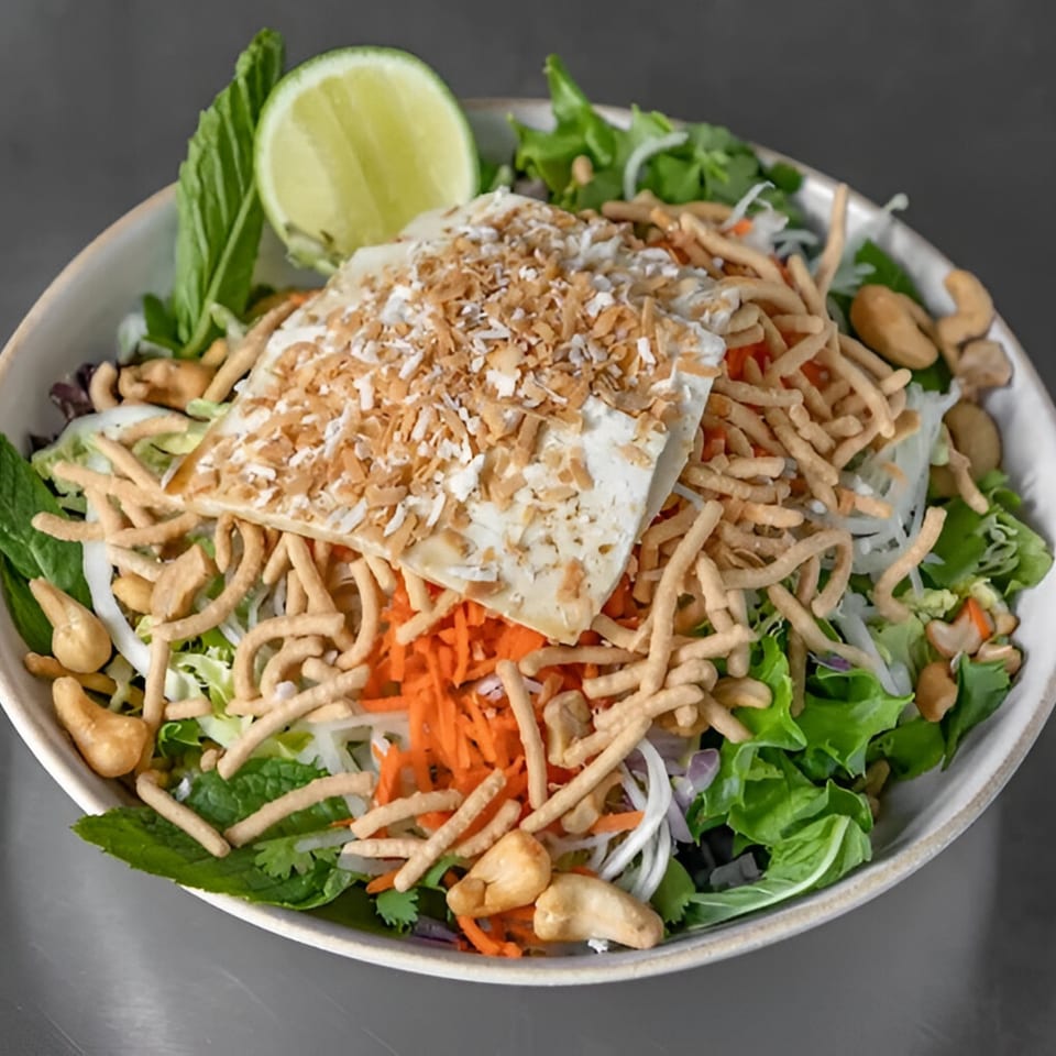 Stoke Salad's vegetarian dish with tofu, crispy noodles, cashews, and a lime wedge.