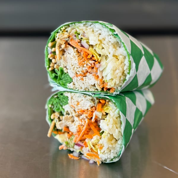 Two halves of a vegetarian burrito, filled with rice, shredded carrots, and other vegetables.